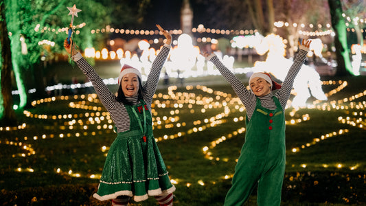 Elves dancing in front of a Christmas light display 